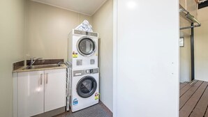 Ein Waschbereich mit gestapelten Waschmaschinen, einem Waschbecken und Schränken.