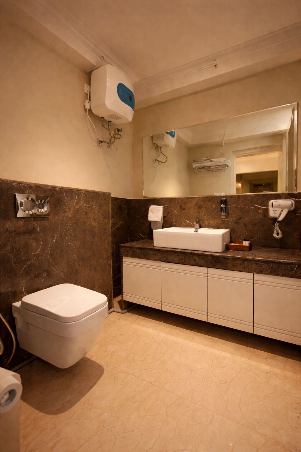 A bathroom with a white toilet, a sink with a marble countertop, and a mirror above the sink.