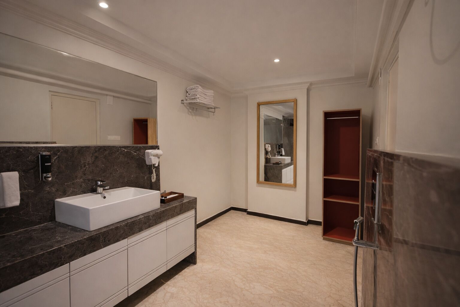 A modern bathroom with a large white sink, marble countertop, and a built-in mirror.