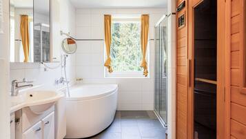 A modern bathroom with a white sink, a freestanding bathtub, a glass shower enclosure, and a window with curtains.