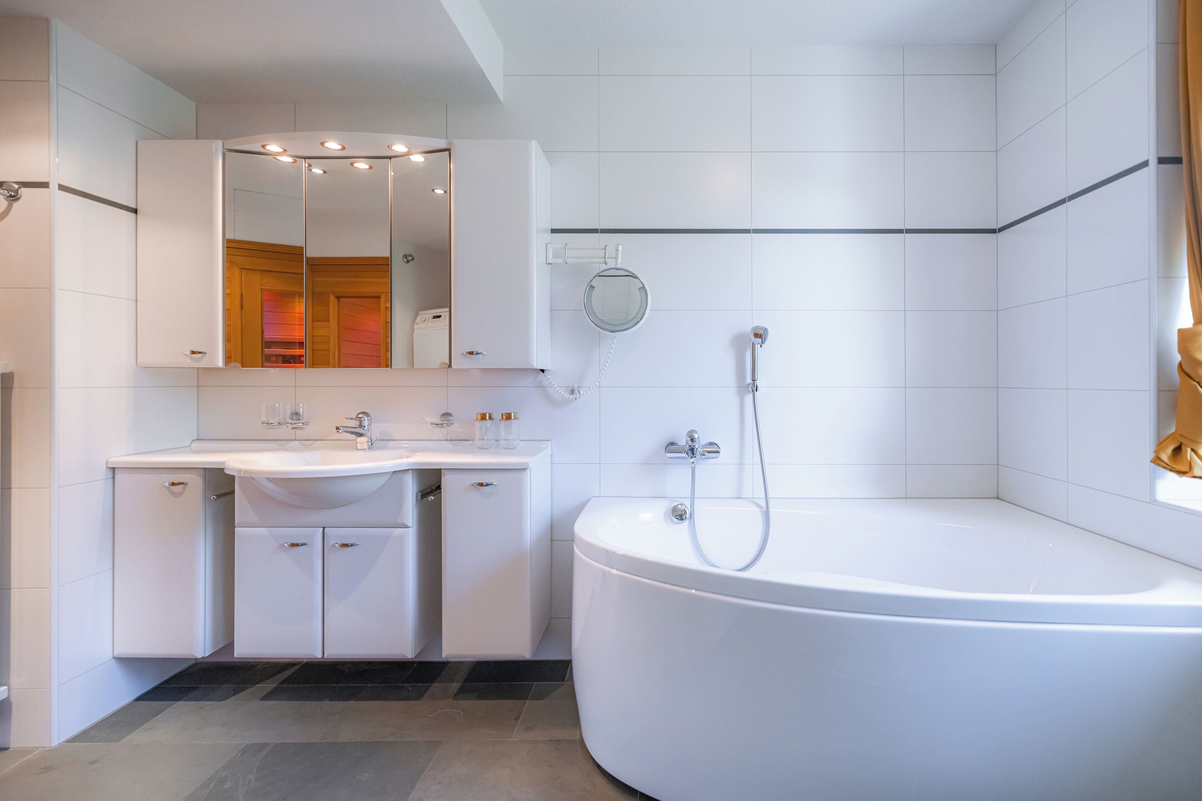 A modern bathroom with a large bathtub, a vanity with a mirror, and a shower area.