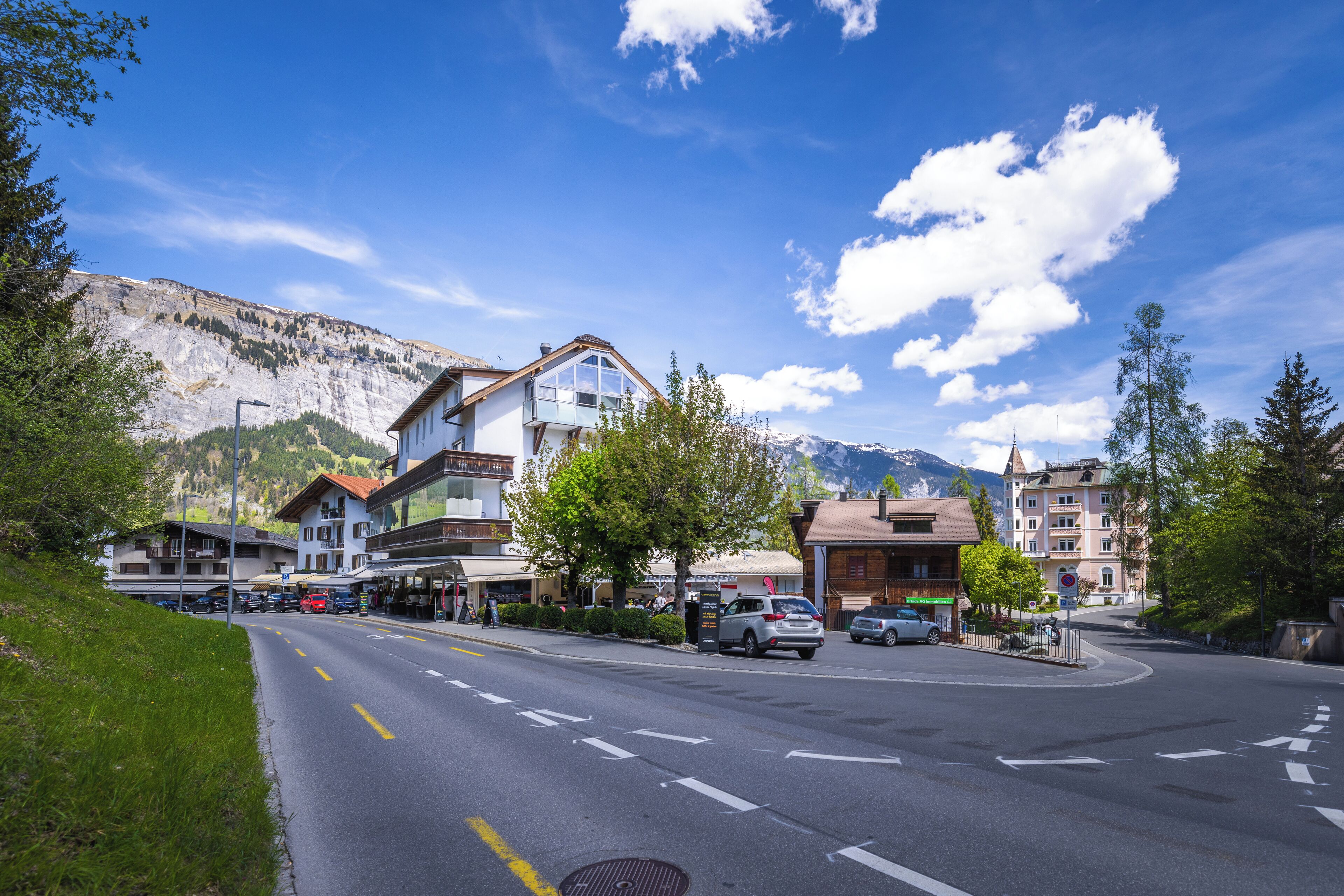 A street with buildings, cars, and a mountain in the background.