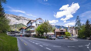 A street with buildings, cars, and a mountain in the background.