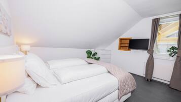 Une chambre à coucher moderne avec un lit, une lampe de chevet, un téléviseur et une fenêtre avec des rideaux.