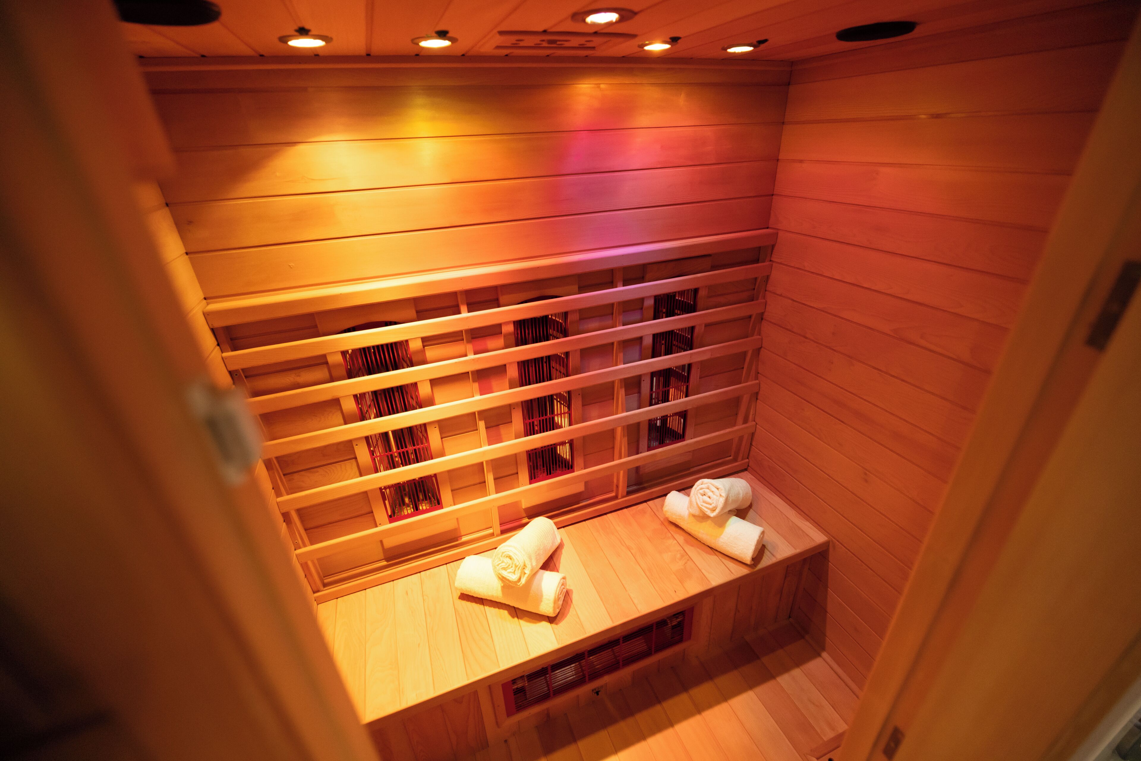En sauna med træbænke og håndklæder lagt på bænke.