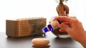 A hand pouring a liquid from a bottle into a small container.