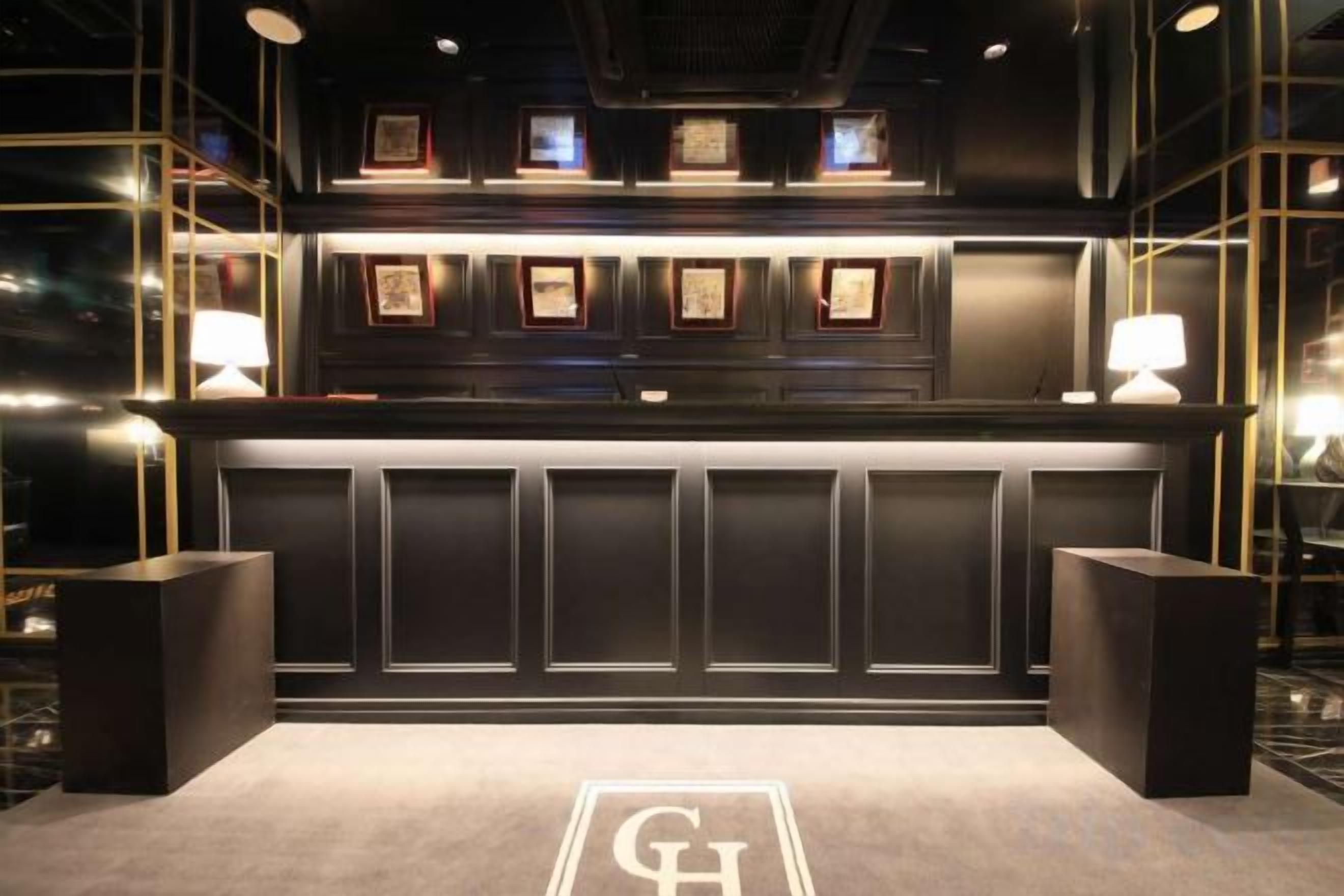 A reception area with a counter, framed awards, and two standing lamps.