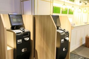 Un espace d’accueil d’hôtel avec deux comptoirs de réception en bois, chacun équipé d’un ordinateur et d’une caisse enregistreuse.