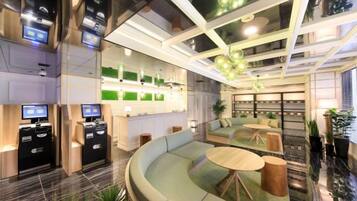A modern hotel lobby with a curved seating area, a reception desk, and a bar area.