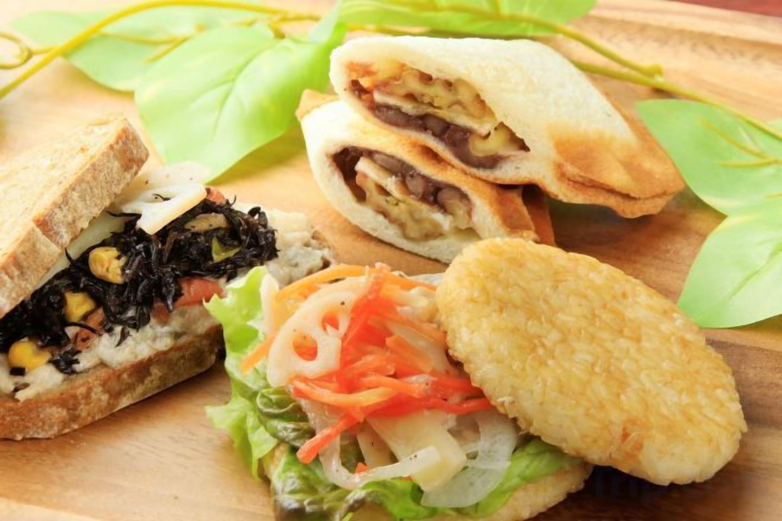 A sandwich cut in half, a breaded item, and a salad on a wooden surface.