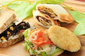 A sandwich cut in half, a breaded item, and a salad on a wooden surface. - Quintessa Hotel Kagoshima Tenmonkan Relax&Sleep (Kagoshima City)