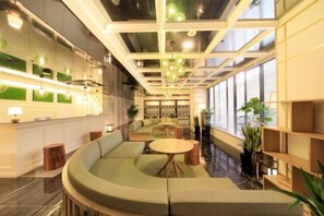 Un moderno vestíbulo de hotel con una zona de estar curva, un mostrador de recepción y grandes ventanales.