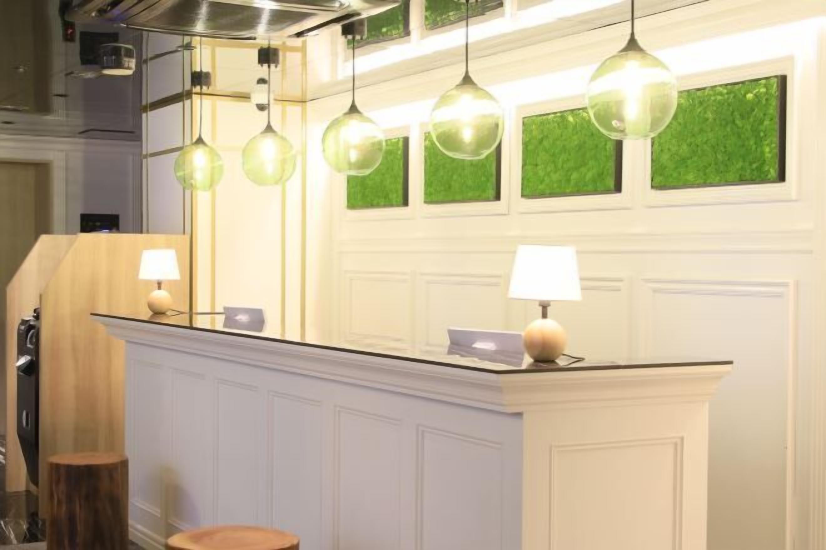 A reception area with a counter, pendant lights, and a wall with green decorative panels.