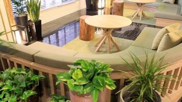 A modern lounge area with a curved seating arrangement, a round table, and potted plants.