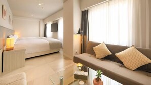A modern hotel room with a bed, a sofa, a coffee table, and a TV.
