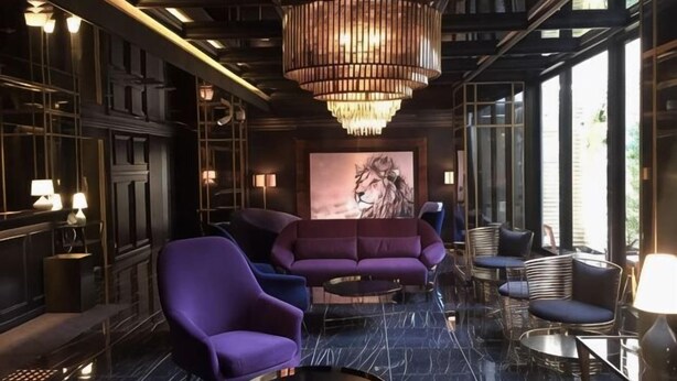 A modern interior with a large chandelier, seating arrangements, and a prominent artwork on the wall.