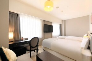 Ein Hotelzimmer mit einem Bett, einem Schreibtisch, einem Sessel, einem Fernseher und einer Lampe.