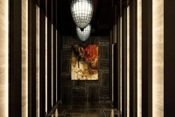 A hallway with a modern light fixture, a textured wall, and a patterned floor.
