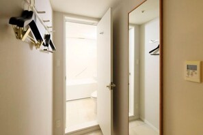 Ein Hotelzimmer mit Bad, Kleiderständer und Wandthermostat.