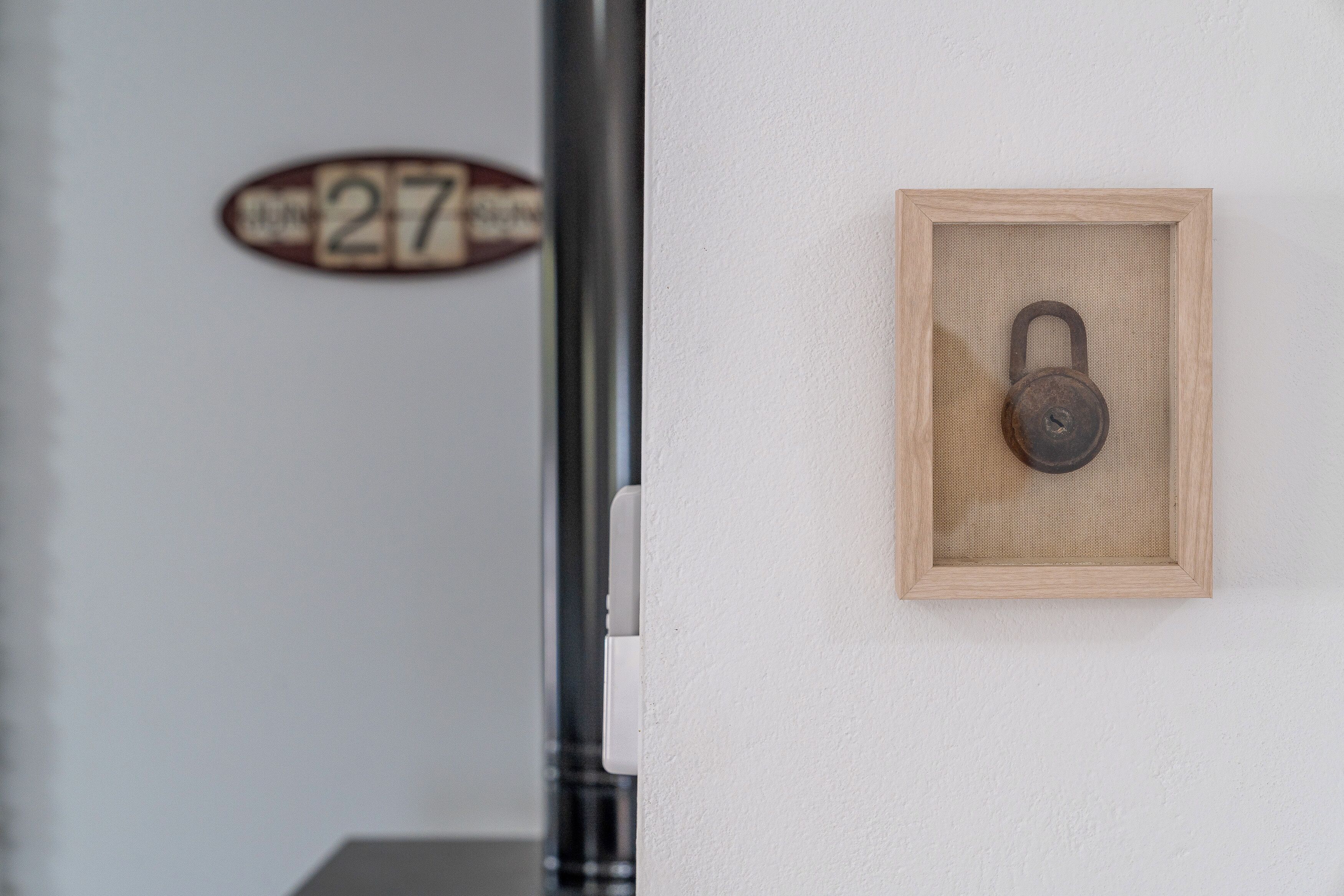 Puerta con un letrero con el número 27 y un candado en la pared.