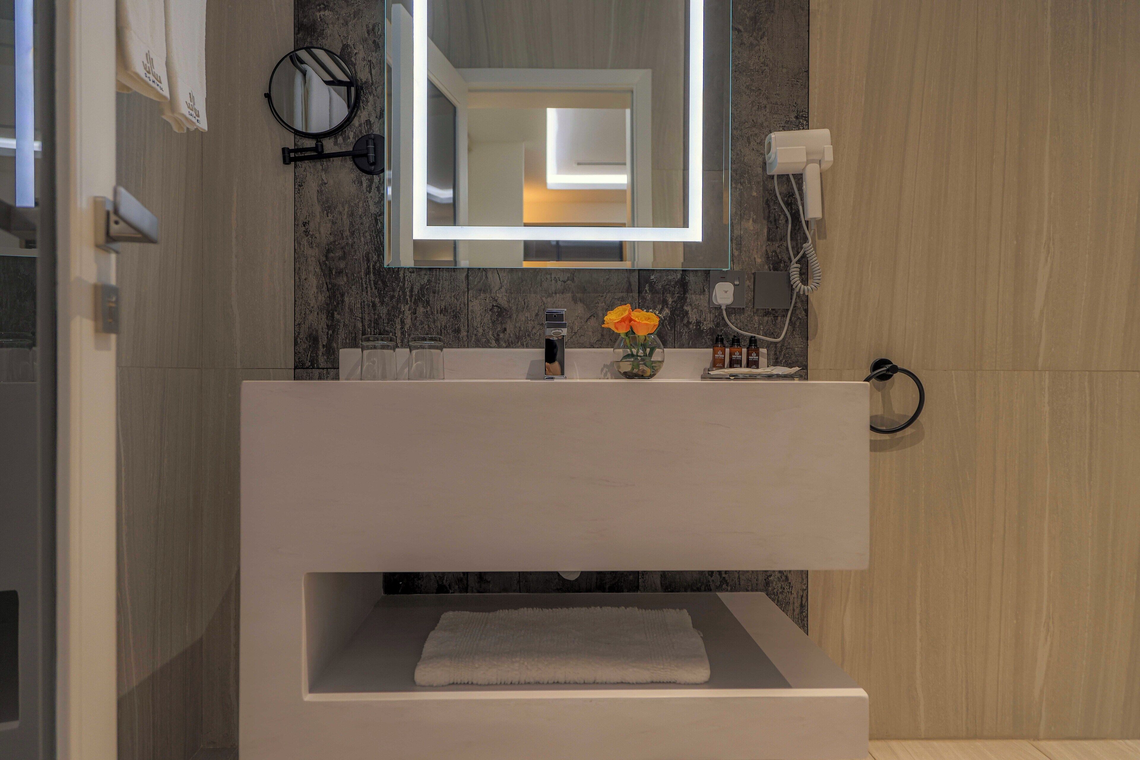 Un bagno moderno con uno specchio grande, un lavandino bianco e un porta asciugamani.