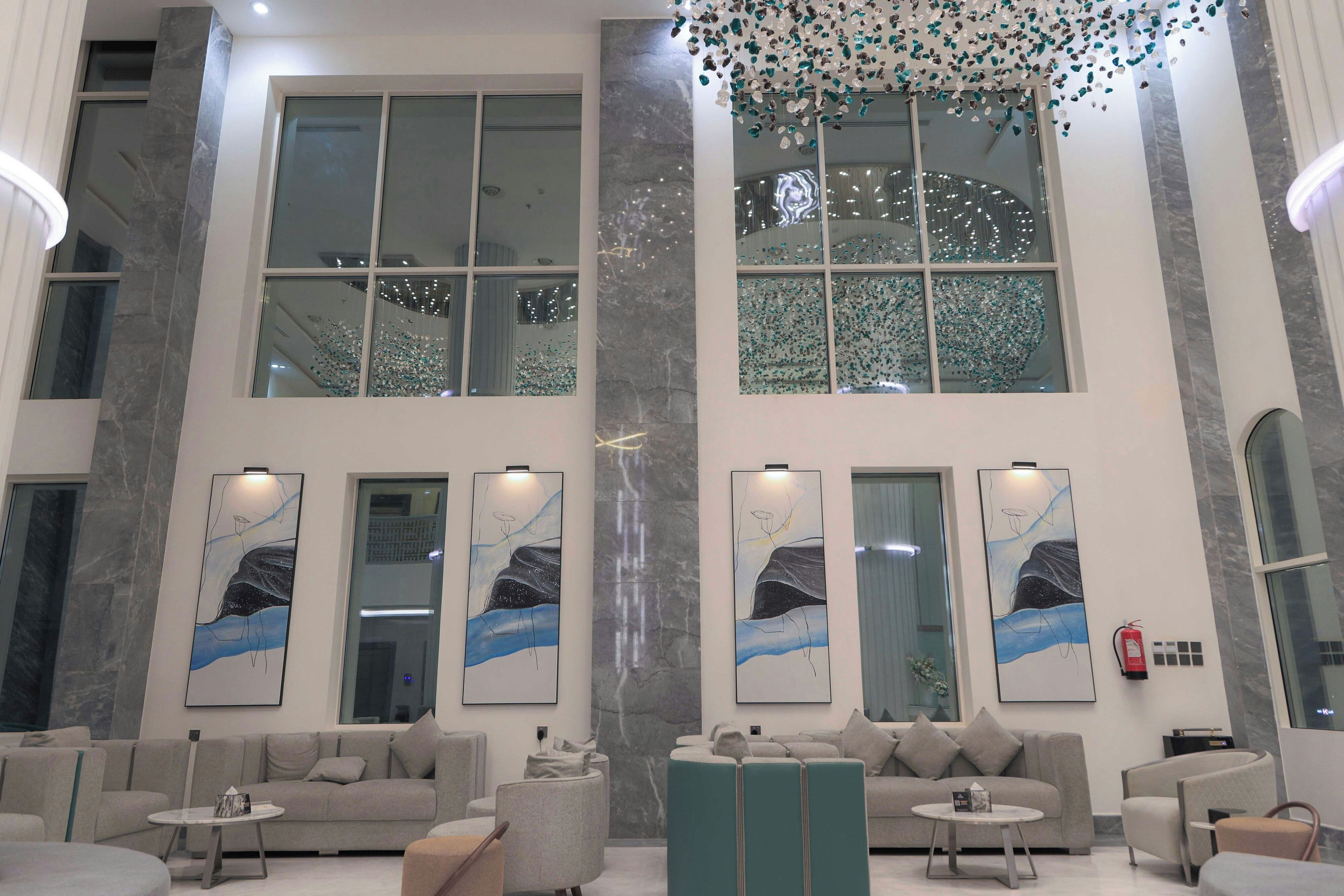 A spacious lobby with high ceilings, large windows, and modern furniture.