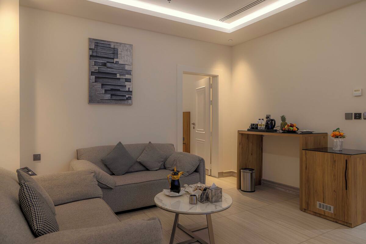 A modern living room with a sofa, a coffee table, and a kitchen area with a counter and cabinets.
