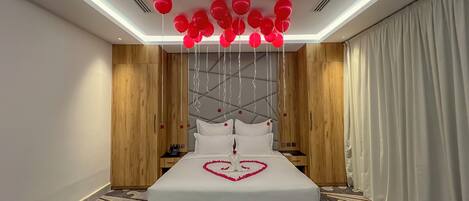 A modern bedroom with a large bed, wooden paneling, and red balloons.