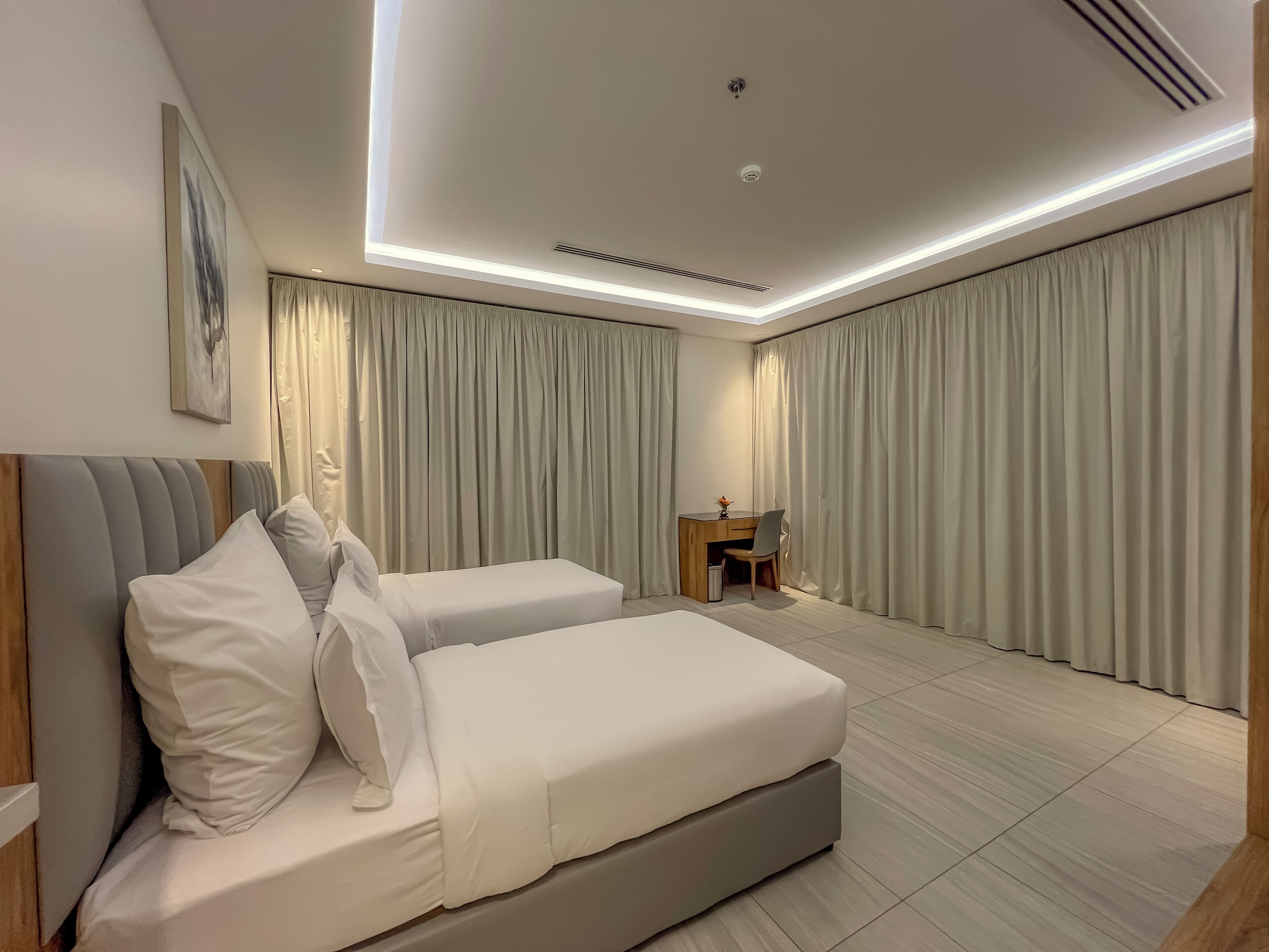 A modern hotel room with a large bed, a desk, and a chair.