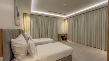 A modern hotel room with a large bed, a desk, and a chair.