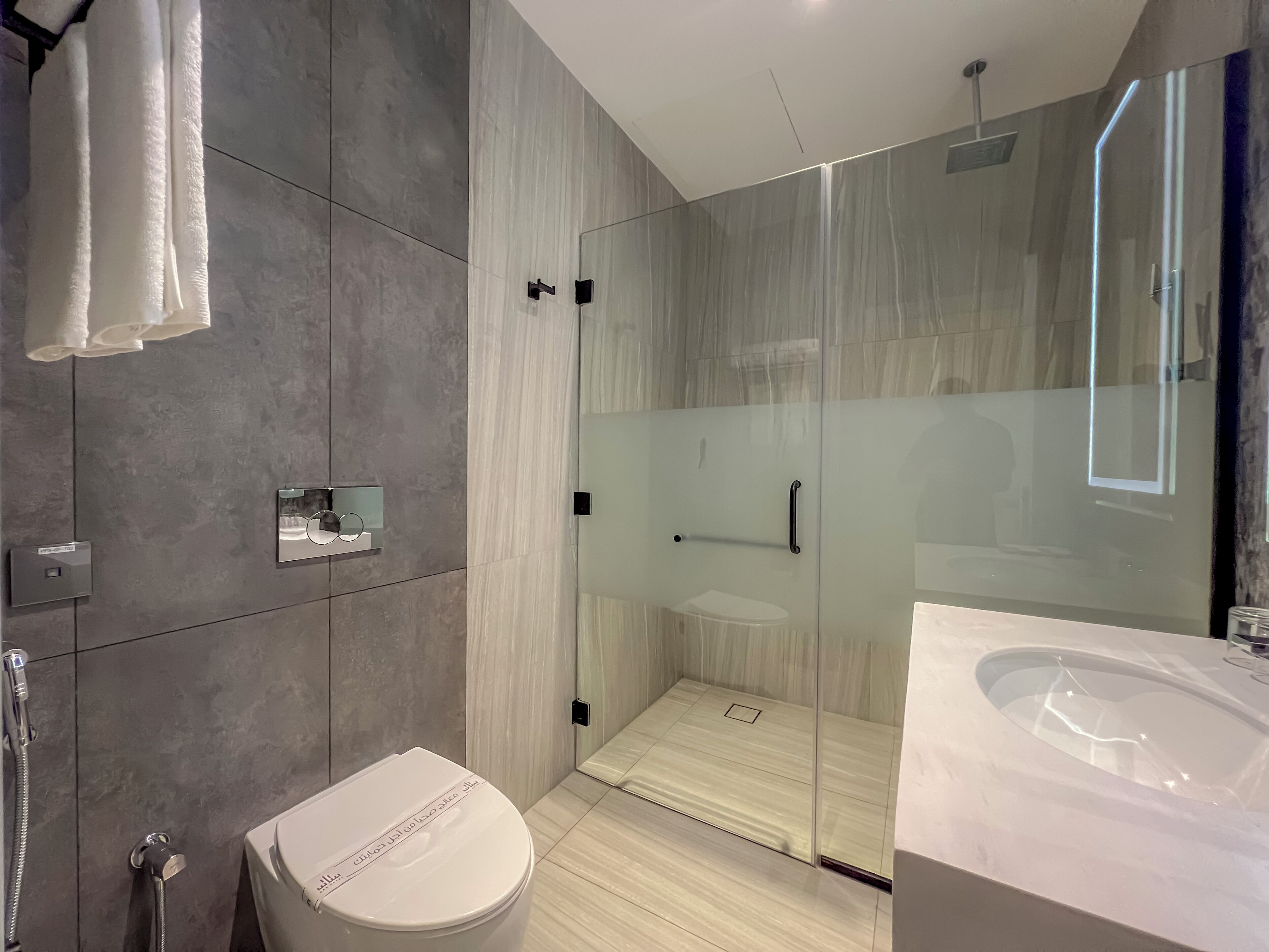 A modern bathroom with a glass-enclosed shower, a large bathtub, and a toilet.