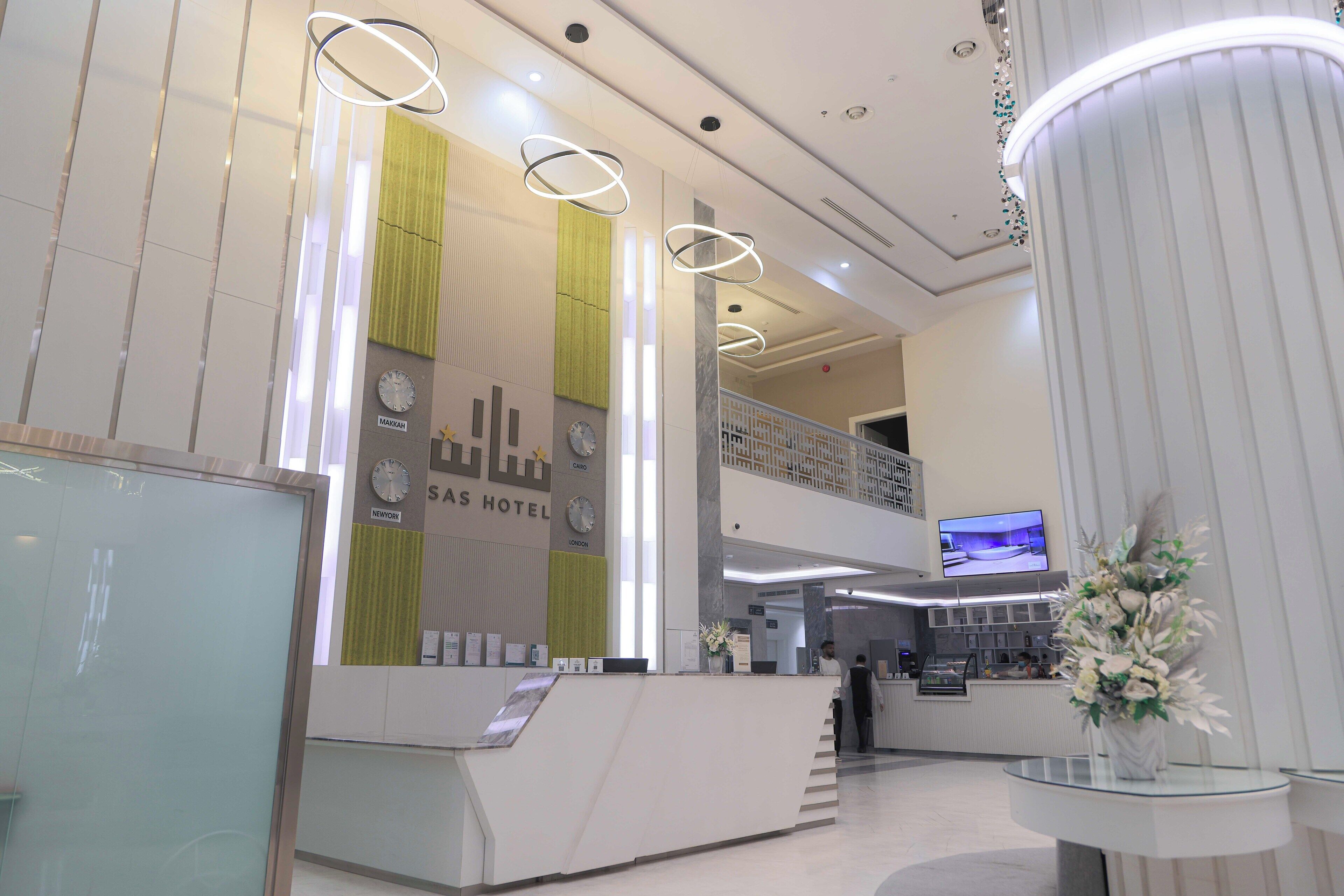 Ein Hotel-Rezeptionsbereich mit modernem Design, inklusive einer Rezeption, einer Uhr und einem Fernsehbildschirm.