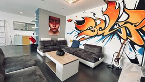 A modern living room with a sectional sofa, a coffee table, and a vibrant graffiti wall. - Maison Individuelle. Animaux de Compagnie Acceptés (Sainte-Cécile-les-Vignes)