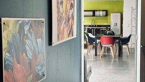 A hallway with three framed paintings on the wall, leading to a dining area with a table and chairs. - Maison Individuelle. Animaux de Compagnie Acceptés (Sainte-Cécile-les-Vignes)