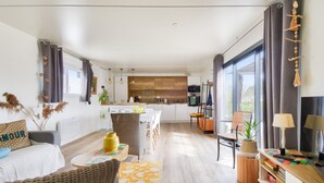 A modern, open-plan living and dining area with a kitchen in the background. - Quiet estate with swimming pool - Chalet for 6 (Bretignolles-sur-Mer)
