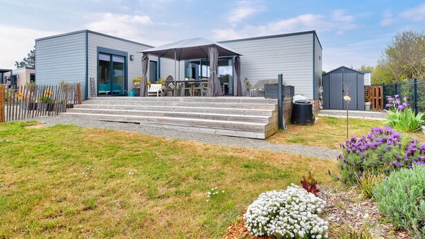 A modern two-story house with a covered patio, a wooden deck, and a garden with various plants. - Quiet estate with swimming pool - Chalet for 6 (Bretignolles-sur-Mer)