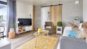 A modern living room with a flat-screen TV, a sofa, a small table, and a decorative plant. - Quiet estate with swimming pool - Chalet for 6 (Bretignolles-sur-Mer)