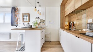 A modern kitchen with white cabinetry, a wooden countertop, hanging pendant lights, and a small island with a plant and a vintage radio. - Quiet estate with swimming pool - Chalet for 6 (Bretignolles-sur-Mer)