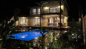 Une maison à deux étages avec une piscine en premier plan.