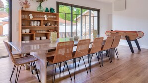 Un coin repas avec une table en verre, des chaises en osier et une bibliothèque en bois.