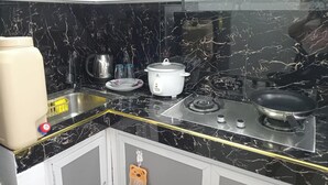 A kitchen with a black marble backsplash, white cabinets, a white stove, and a white slow cooker. - 3g's & C Calapan Transient House (Calapan)