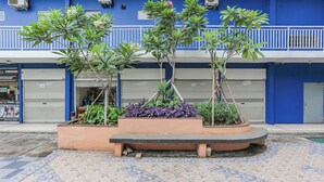 A blue building with a balcony, a planter with plants, and a tiled ground. - Hotel O Dms Property (Bekasi)