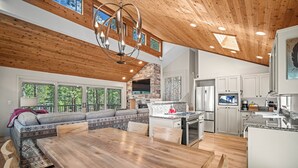 Une cuisine spacieuse dotée d’un grand îlot central, d’un plafond en bois et d’appareils électroménagers intégrés.