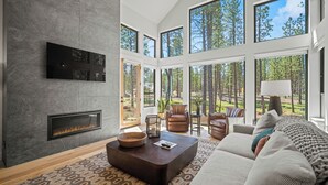 A spacious living room with a fireplace, large windows, and a cozy seating area. - Family-Friendly Caldera Retreat with Access to Exclusive Golf (Bend)