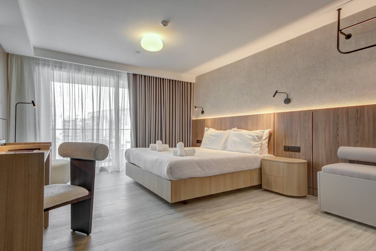A modern hotel room with a large bed, bedside tables, a desk, and a chair.