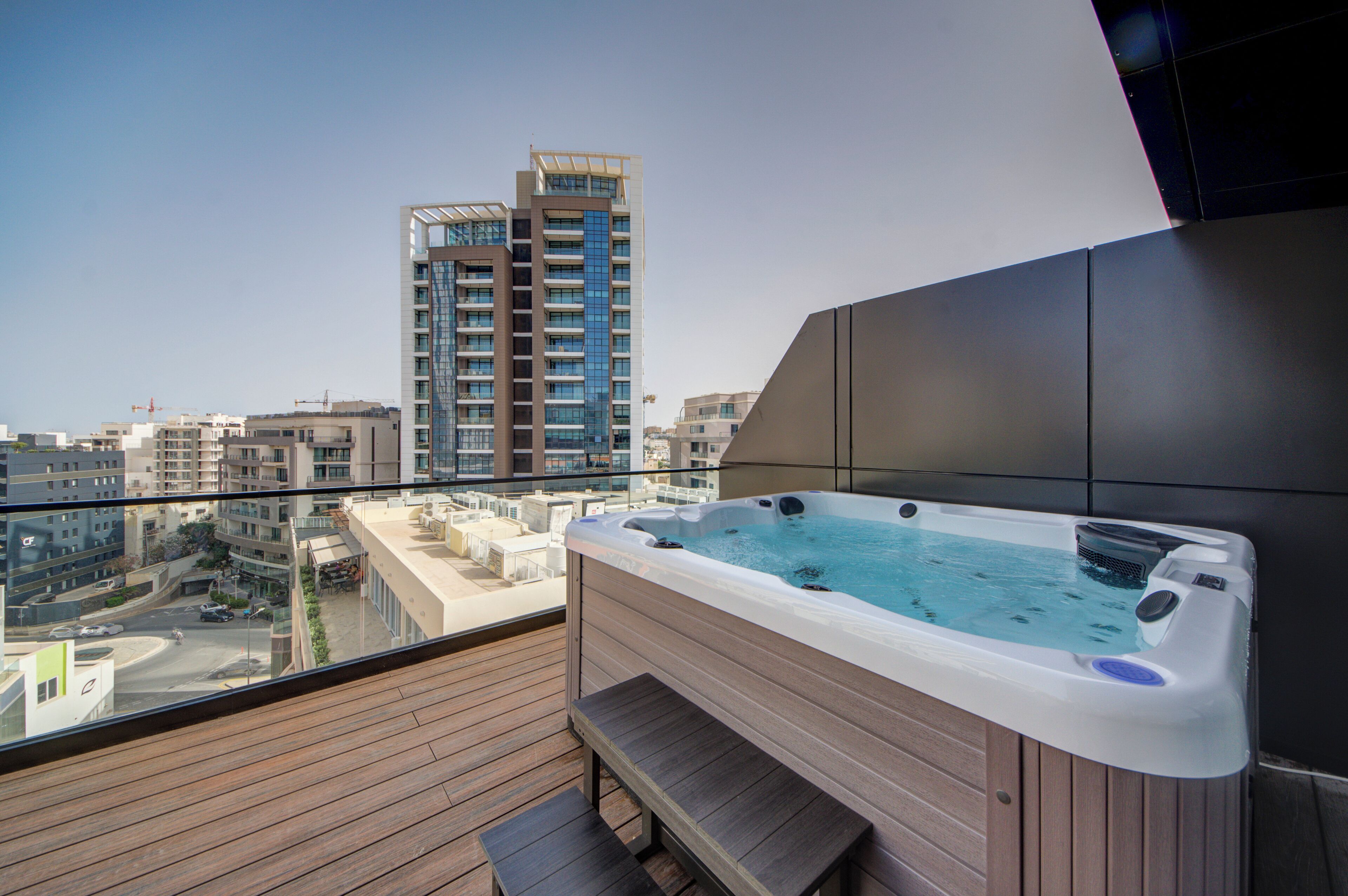 Ein Balkon mit Whirlpool, Holzboden und Blick auf die Stadt.