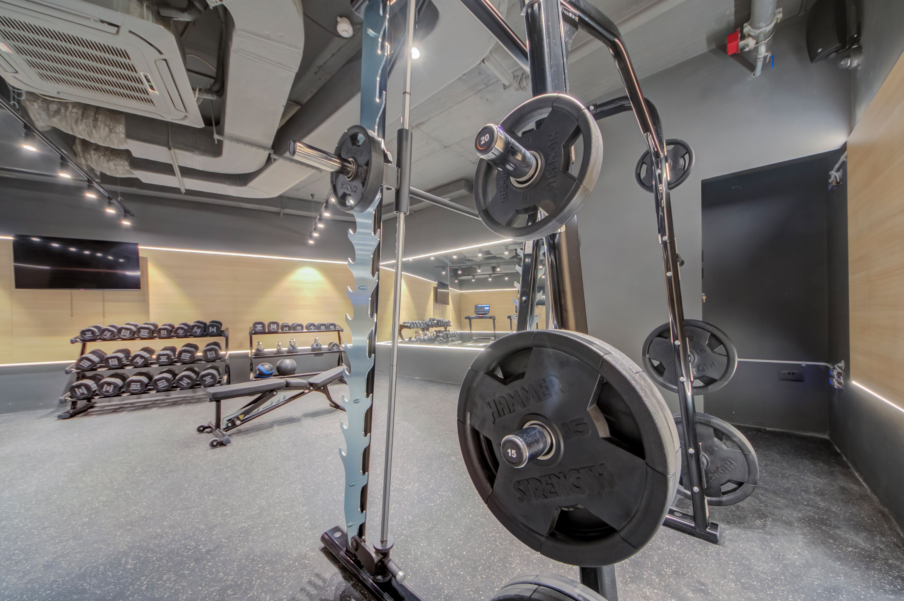 Een sportschool met gewichthefapparatuur, halters en een spiegel.