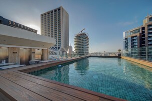 Una piscina en la azotea con sillones de descanso y vistas a edificios altos.