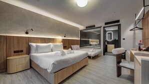 Una habitación de hotel moderna con una cama grande, mesitas de noche, un escritorio y un espejo.