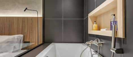 A modern bathroom with a freestanding bathtub, a wooden vanity, and a large mirror.